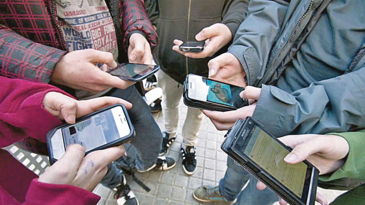  Un grupo de jóvenes intercambia mensajes con sus teléfonos móviles. 