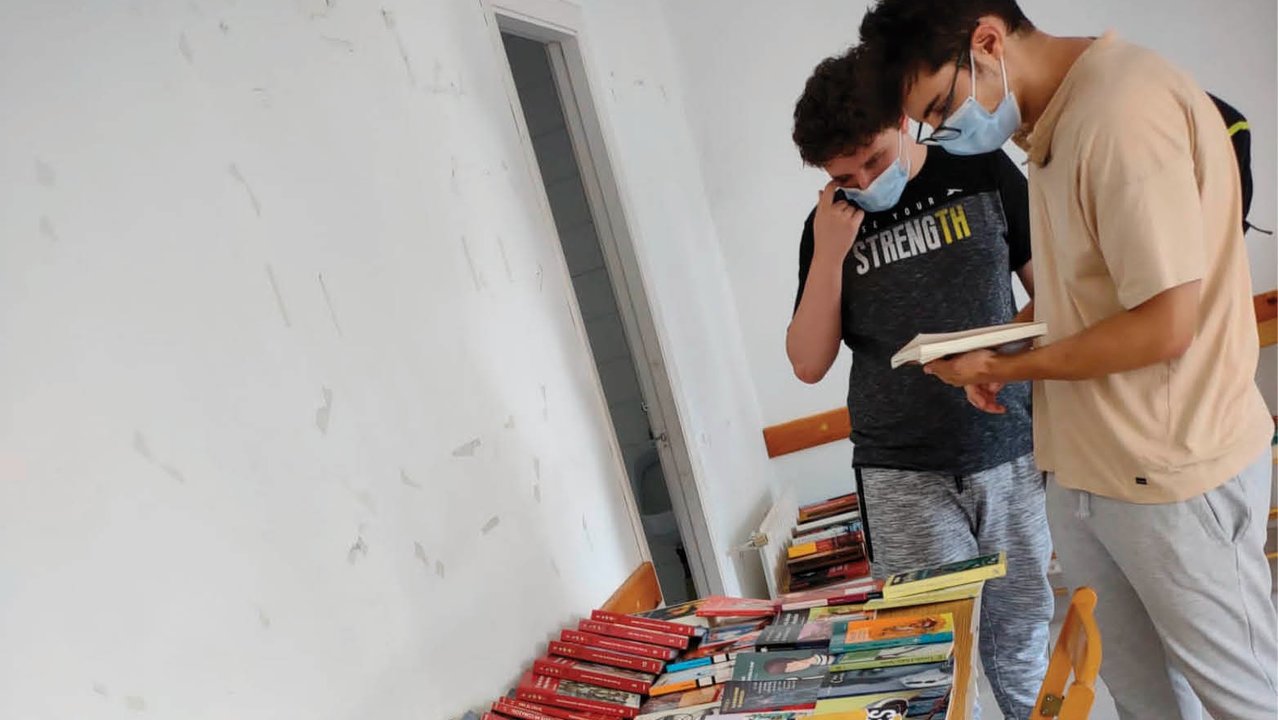 Dos jóvenes consultan libros en la biblioteca de Macendo.