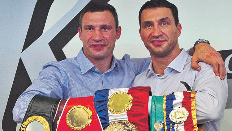 Los hermanos Klitschko posan con sus cinturones de campeones mundiales de boxeo.