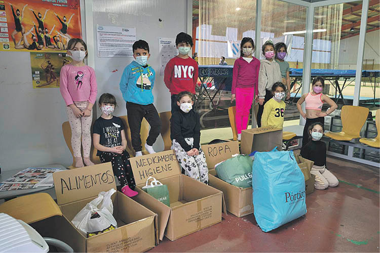 Niños del Club Ximnasia Pavillón, frente a las cajas de ayuda que empezaron a recoger ayer (ÓSCAR PINAL).