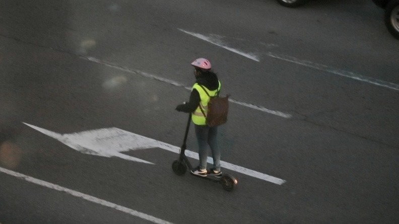 Foto de archivo de una mujer circulando con un patinete eléctrico.
