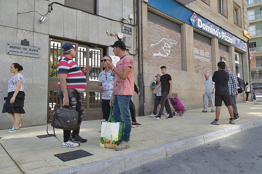 Usuarios del comedor social de Cáritas de la ciudad, frente a la entrada del local. (MARTIÑO PINAL)