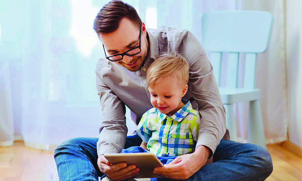 Un niño juega con su padre a la tablet.