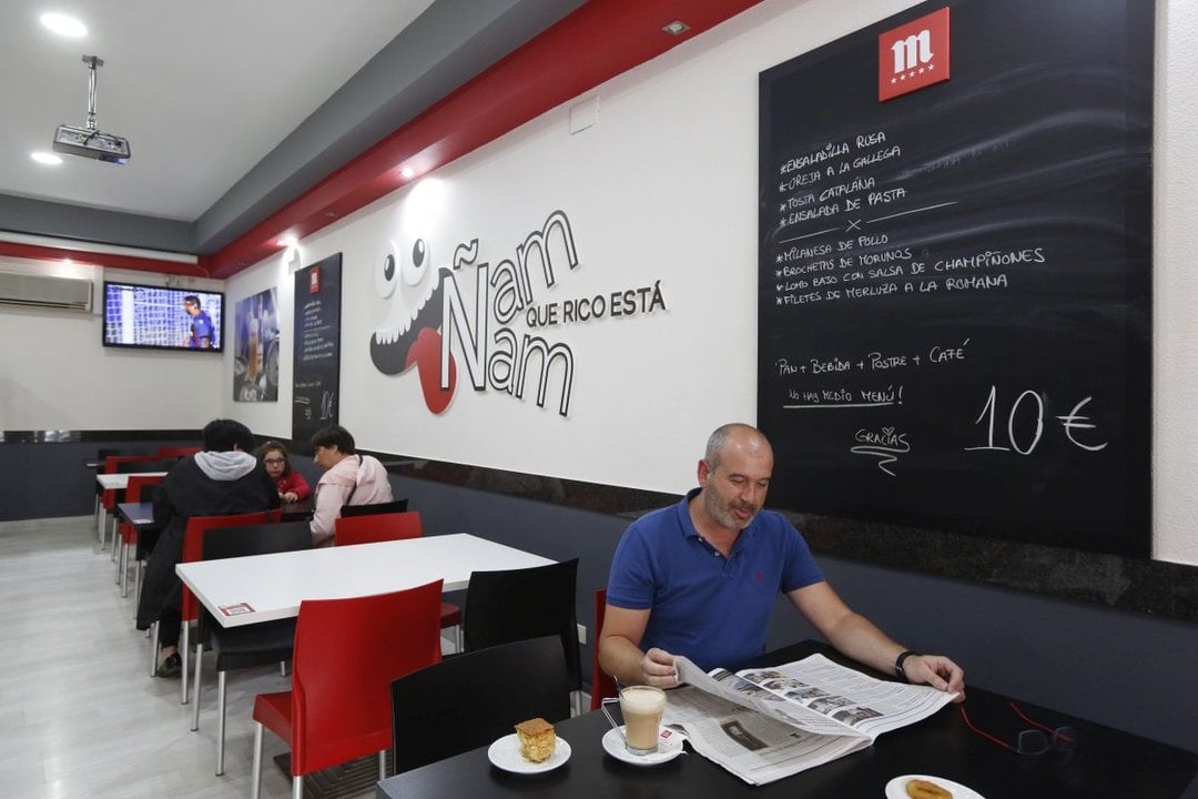 Un hombre lee el diario La Región en una cafetería ourensana. XESÚS FARIÑAS