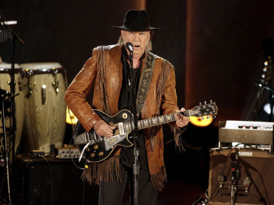 El músico canadiense Neil Young toca la guitarra durante una actuación.
