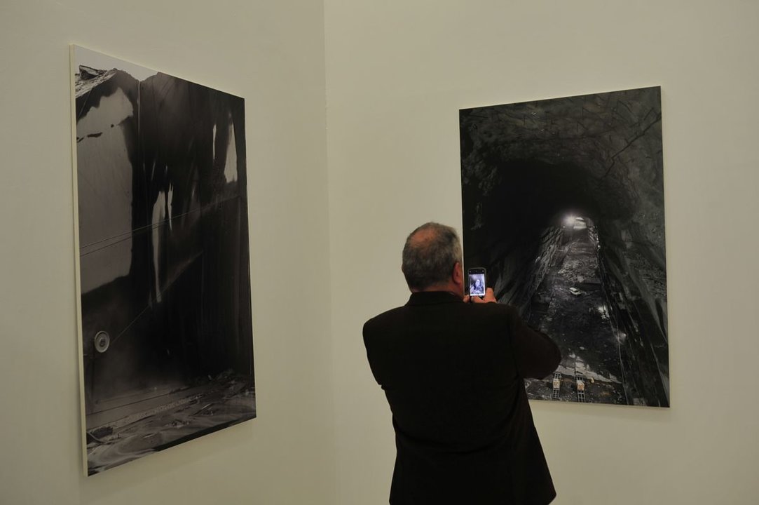 Un hombre toma una foto con su móvil a una de las imágenes de la exposición.