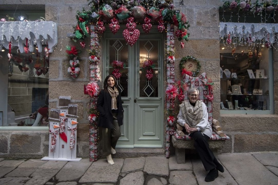 Flor y Sira fuera de la tienda, con el decorado navideño.