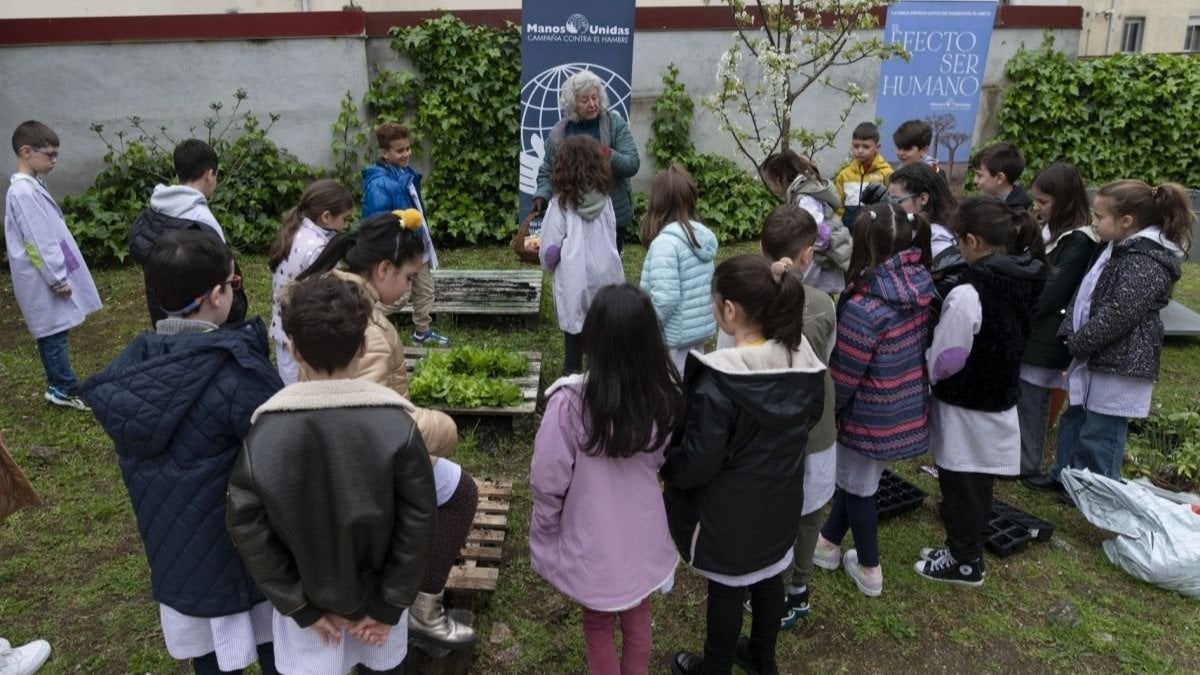 Carmen Freire, de Manos Unidas, con los alumnos de San Pío X explicando la huerta ecodidáctica. (Foto: Martiño Pinal)