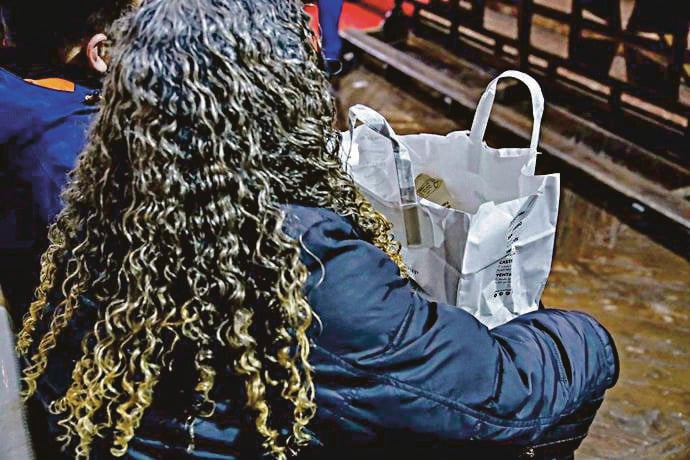 Una mujer recoge una bolsa de comida en una iglesia.