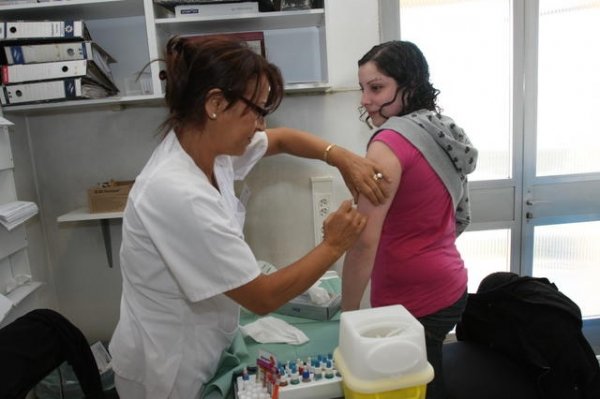 Una enfermera pone una vacuna a una joven que sufre alergia.