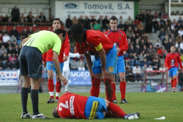 Seoane, lesionado en el suelo, es atendido por el árbitro y Aloisio, mientras observan Yebra y Portela.