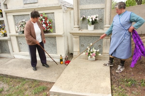 La botella de champán, el centro de flores y las velas negras y rojas, junto a una lápida. (Foto: Miguel Angel)