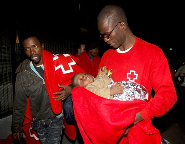 Miembros de la Cruz Roja trasladan a un bebé llegado en la patera. (Foto: Carlos Barba)