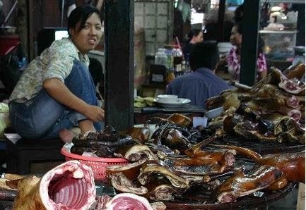 Una mujer vende perros asados en un puesto de comida de un mercado camboyano.