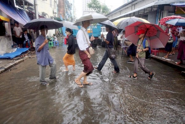 Un grupo de personas pasa por una calle anegada por las intensas lluvias.