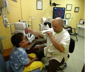 Un óptico realiza una revisión a un niño.