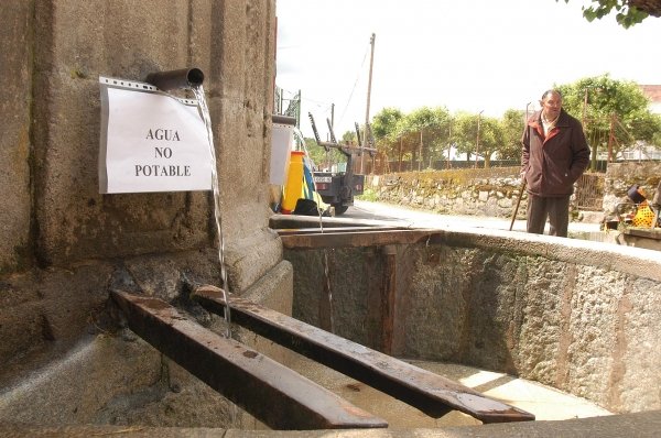 Dos carteles advierten de la contaminación del agua en la fuente de Flores. (Foto: Martiño Pinal)