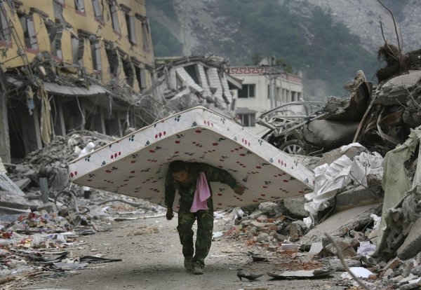Un ciudadano chino transporta un colchón rescatado de los escombros de su ciudad.