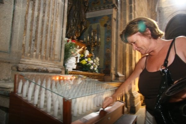 Una mujer inserta una moneda para las velas que hay ante el San Antonio, en la Catedral. (Foto: Xesús Fariñas)