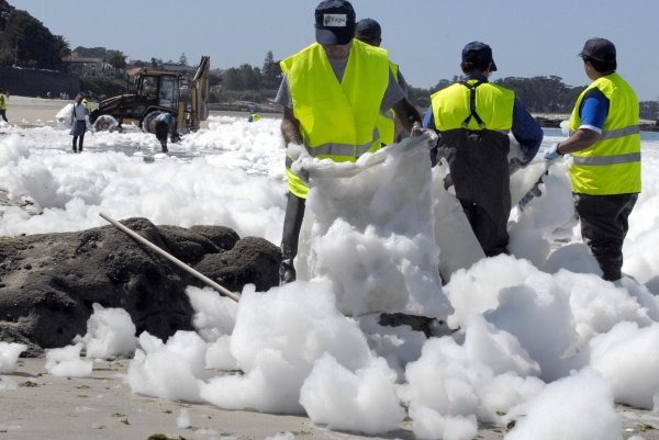 Los miembros de las brigadas de limpieza retiran la espuma de la playa de Samil. (Foto: Pablo Araújo)