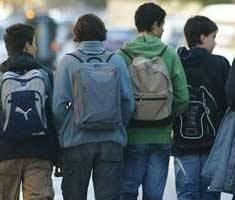 Varios niños acuden al colegio con sus respectivas mochilas.