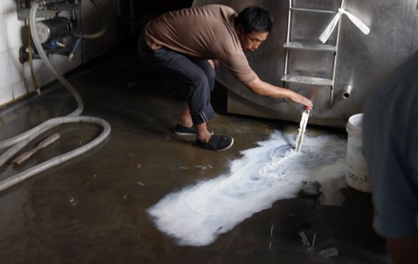 Un productor lácteo chino vacía un tanque de leche. (Foto: Ng Han)