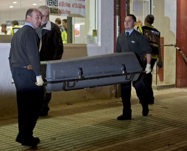 Trabajadores de una funeraria trasladan el cadáver del atracador. (Foto: J.M. Vidal)