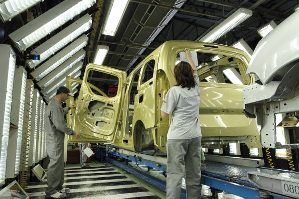 Trabajadores de PSA en Vigo revisan uno de los vehículos en la cadena de montaje.