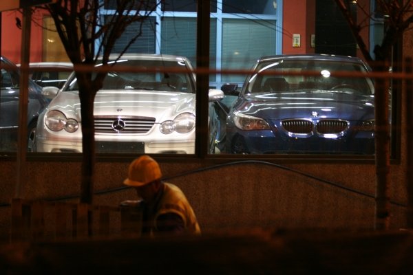 Un obrero trabaja frente a un concesionario que exhíbe vehículos de alta gama. (Foto: Xesús Fariñas)