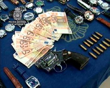 Una pistola, munición, relojes, y dinero que la Policía Nacional se ha incautado a raíz del desmatelamiento de cinco tiendas virtuales.