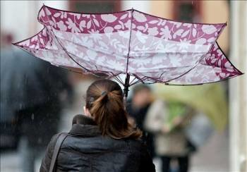 Un mujer intenta protegerse de la lluvia y el viento con su paraguas por el centro de Sevilla. (Foto: Julio Muñoz)