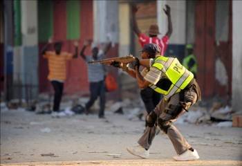 Un oficial de la Policía haitiana dispara a un grupo de hombres que fueron sorprendidos cometiendo actos de pillaje.