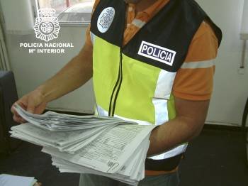 Un policía muestra los papeles intervenidos a una red de falsificación de permisos para inmigrantes. (Foto: Archivo)