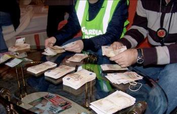 Agentes de la Guardia Civil manipulan parte de los 500.000 euros encontrados en el jacuzzi de una lujosa vivienda de El Puerto de Santa María. (Foto: EFE)