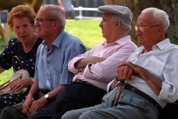 Un grupo de jubilados pasan el rato en un parque.