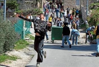 Manifestantes palestinos lanzan piedras a los soldados israelíes durante la protesta en contra de la construcción del muro israelí en Cisjordania. (Foto: ABED AL HASHLAMOUN)