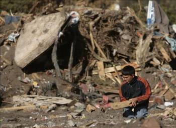 Un niño busca entre los escombros de su casa. (Foto: LEO LA VALLE)