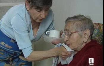 Una mujer atiende a una anciana dependiente, a la que ayuda a comer. (Foto: Archivo)