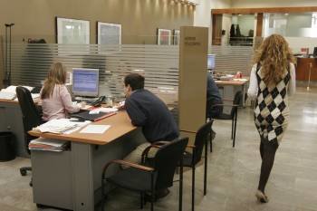 La empleada de una entidad bancaria de la ciudad atiende las consultas de un cliente. (Foto: XESÚS FARIÑAS)