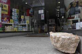 A la derecha, la piedra utilizada por los ladrones para romper la puerta de la Perfumería 'Muchas'. (Foto: XESÚS FARIÑAS)