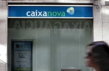 Un letrero de Caixa Galicia se refleja en el cristal de una oficina de Caixanova en A Coruña.