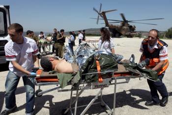 Soldados israelies trasladan en camilla a varios heridos tras el asalto.