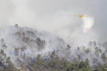 Una avioneta descarga agua sobre la masa forestal que ardía en Arnoia.