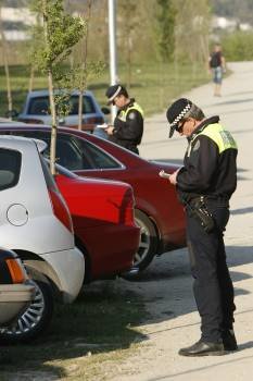 Dos policías locales multan sendos vehículos.
