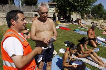 Un bañista recibe el folleto informativo de Cruz Roja