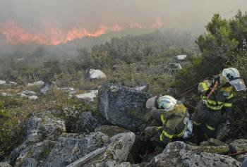 Dos bomberos (a la derecha) marchan en busca de refuerzos, ante el frente de llamas en un monte de Cobas, el año pasado.