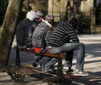 Cuatro jóvenes, sentados en el banco de un parque.