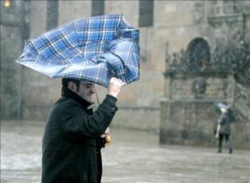 Una persona se resguarda de los fuertes vientos y la lluvia en la Plaza del Obradoiro, en Santiago de Compostela
