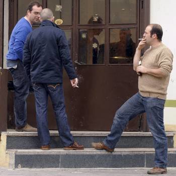 Tres hombres fuman ante la puerta de un bar en Valladolid. (Foto: Nacho Gallego)