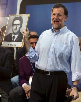 Rajoy muestra el retrato de su orla que le entregó un militante del partido. (Foto: JOSÉ MANUEL VIDAL)